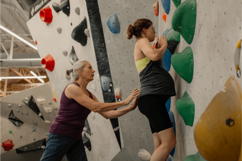 odyspot beim Bouldern in der Schwangerschaft: Spotter begleitet einen Zug knapp über der Matte