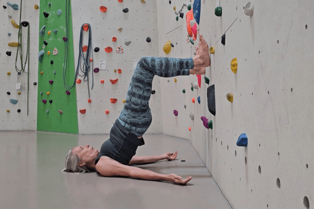 Schulterbrücke mit Fußsohlen an der Wand als Heel Hook Vorbereitung nach der Geburt